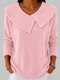 Woman wearing a light pink long sleeve knit top with a large fold-over pointed collar, deep V neckline and ribbed cuffs, with white trousers._0