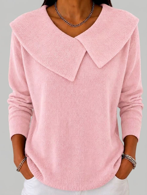 Woman wearing a light pink long sleeve knit top with a large fold-over pointed collar, deep V neckline and ribbed cuffs, with white trousers._0