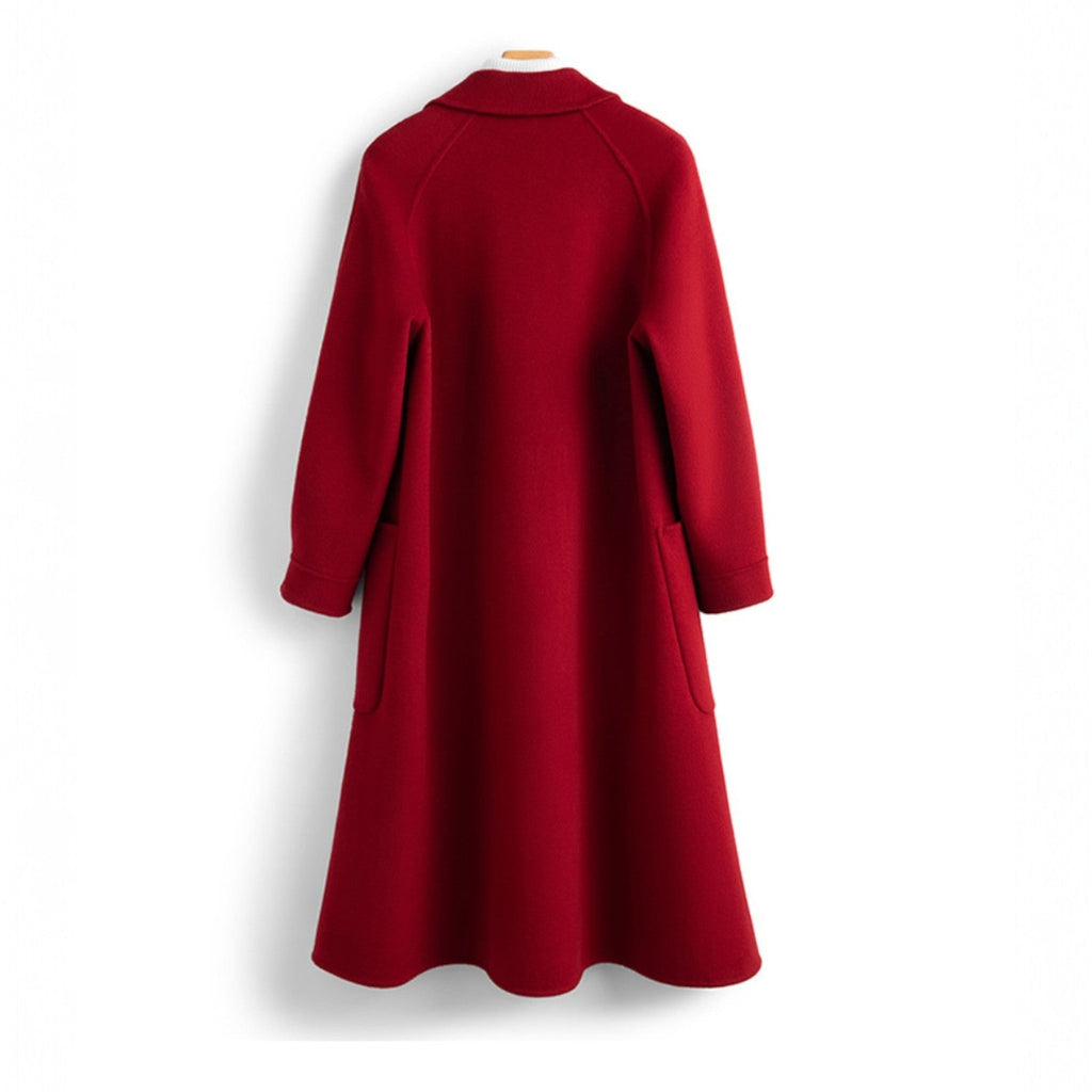 A long double breasted coat with wide lapels and front patch pockets displayed on a hanger._1