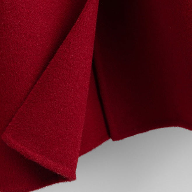 A long double breasted coat with wide lapels and front patch pockets displayed on a hanger._5