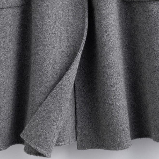 A long double breasted coat with wide lapels and front patch pockets displayed on a hanger._8