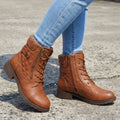 Pair of tan lace-up ankle boots with quilted panels, knit collars, side zips, and low block heels worn with light blue jeans on pavement._0