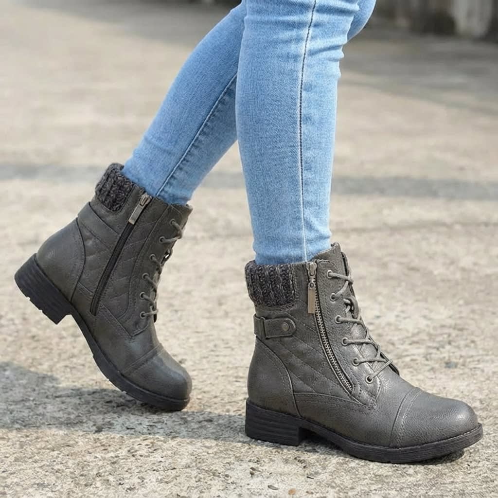 Pair of tan lace-up ankle boots with quilted panels, knit collars, side zips, and low block heels worn with light blue jeans on pavement._4