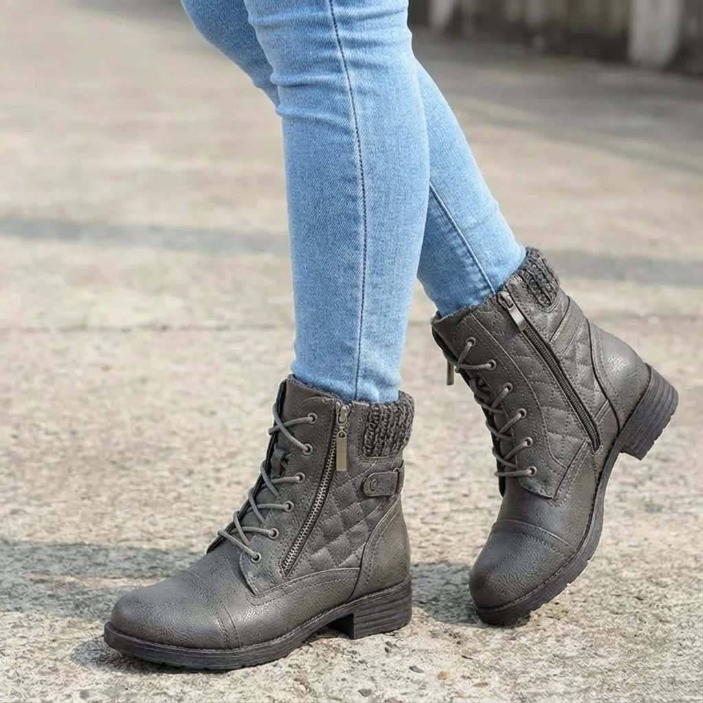 Pair of tan lace-up ankle boots with quilted panels, knit collars, side zips, and low block heels worn with light blue jeans on pavement._5