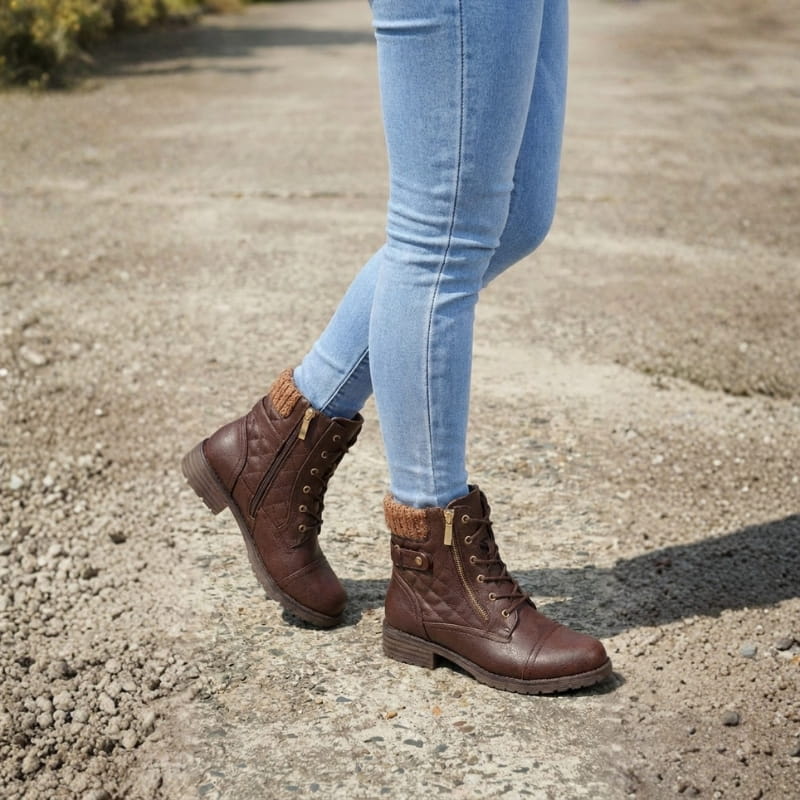 Pair of tan lace-up ankle boots with quilted panels, knit collars, side zips, and low block heels worn with light blue jeans on pavement._7
