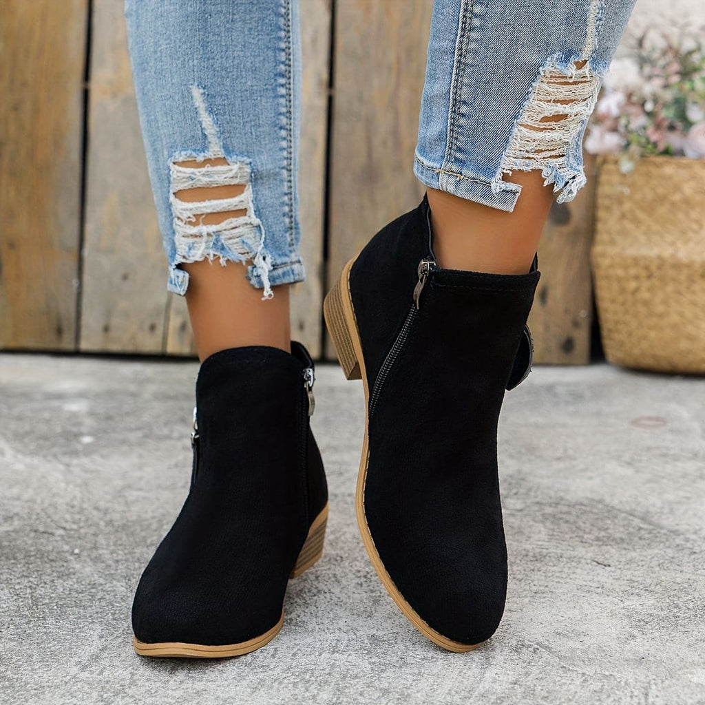 Woman wearing ankle boots with side zippers and a low stacked heel, styled with distressed jeans._1