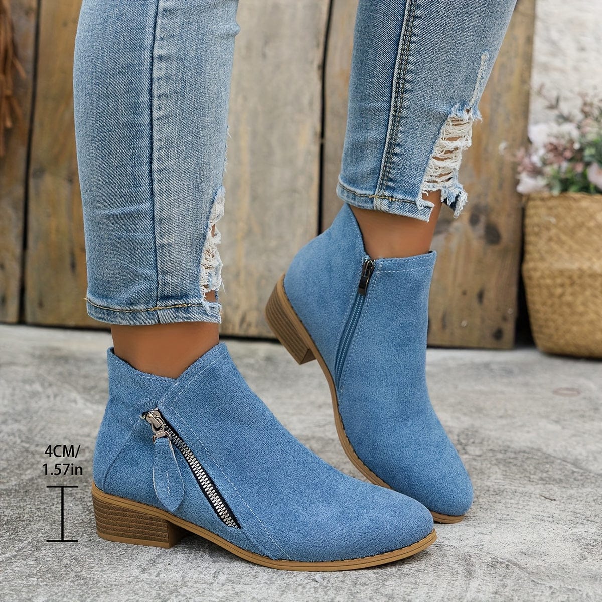 Woman wearing ankle boots with side zippers and a low stacked heel, styled with distressed jeans._2