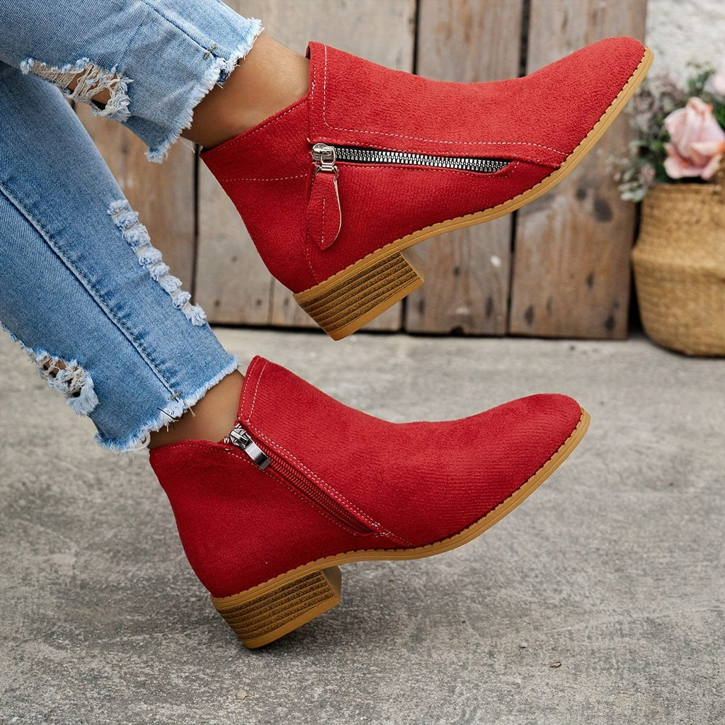 Woman wearing ankle boots with side zippers and a low stacked heel, styled with distressed jeans._3