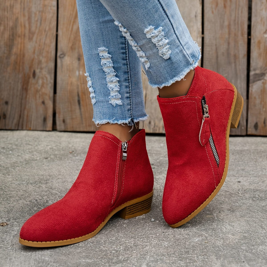 Woman wearing ankle boots with side zippers and a low stacked heel, styled with distressed jeans._8