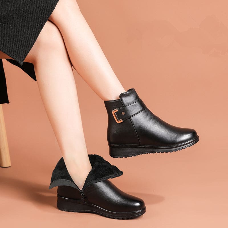 Close-up of a black ankle boot with a buckle strap detail and cushioned sole._2
