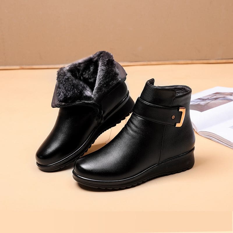 Close-up of a black ankle boot with a buckle strap detail and cushioned sole._4