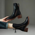 Black ankle boots displayed against a dark background, highlighting their sleek uppers, side zippers, and stacked block heels.