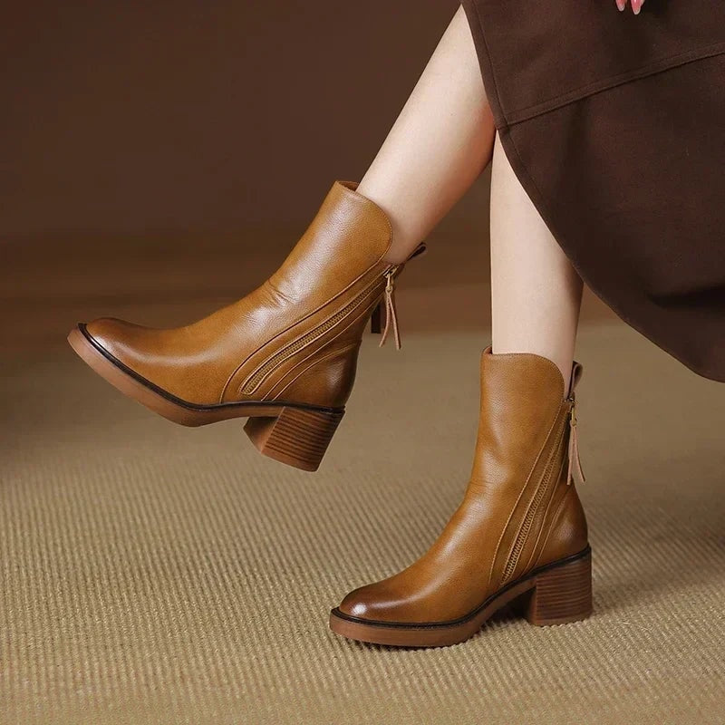 Tan ankle boots styled with a brown skirt, featuring side zips, pointed toes, pull tabs, and brown block heels.