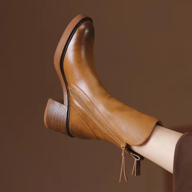 Pair of black mid-calf boots with gold side zips, brown stacked block heels and rounded toes on a white plinth._3