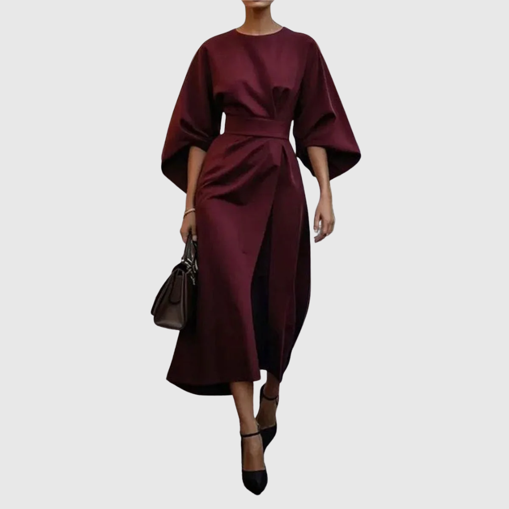Woman wearing an ankle-length belted dress with wide dolman sleeves in a minimalist setting_1