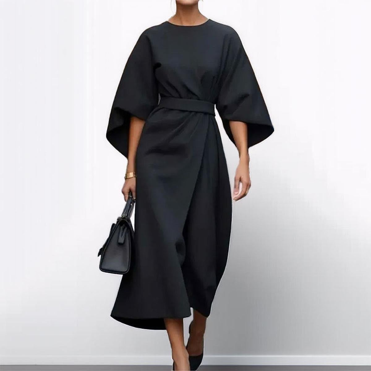 Woman wearing an ankle-length belted dress with wide dolman sleeves in a minimalist setting_2