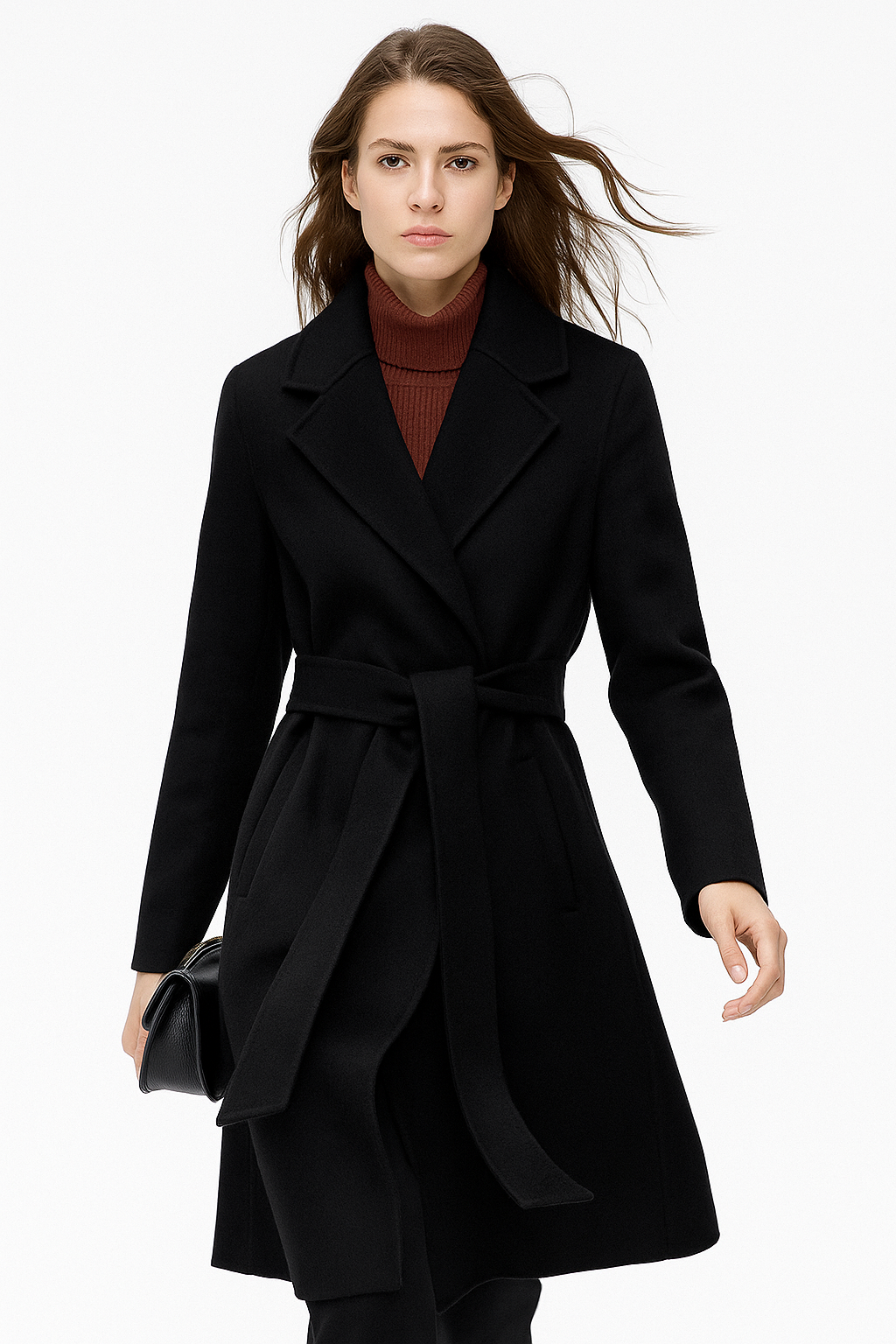 Woman wearing a camel belted midi coat with tie waist over a turtleneck and black trousers, standing in natural light._19
