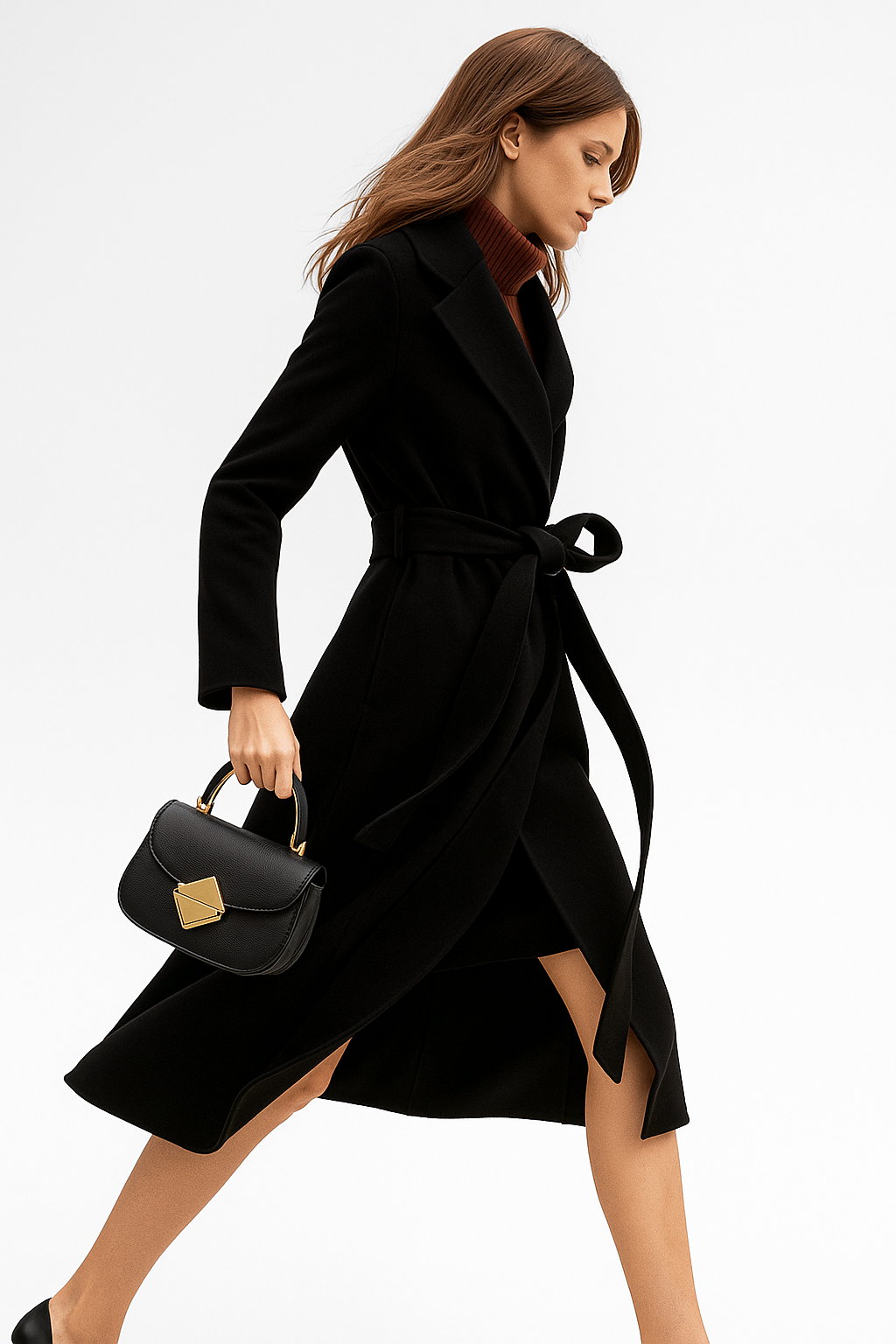 Woman wearing a camel belted midi coat with tie waist over a turtleneck and black trousers, standing in natural light._21