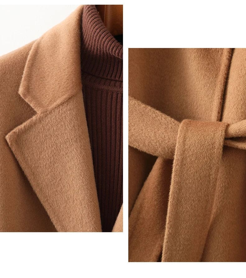 Woman wearing a camel belted midi coat with tie waist over a turtleneck and black trousers, standing in natural light._25