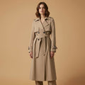 Woman wearing a belted trench coat in a classic silhouette with double-breasted front and tie waist against a neutral background._0