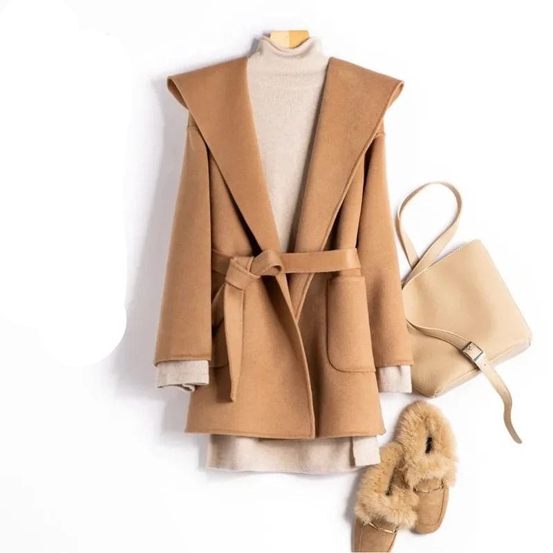 Woman wearing a belted wrap coat with a wide shawl collar, tie belt, and patch pockets over a turtleneck and trousers._17