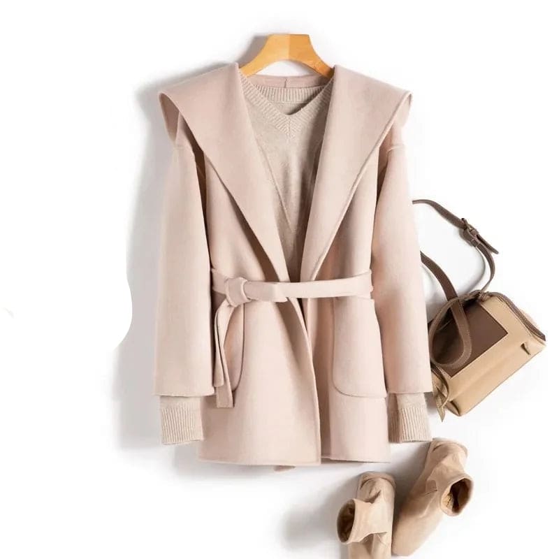 Woman wearing a belted wrap coat with a wide shawl collar, tie belt, and patch pockets over a turtleneck and trousers._18