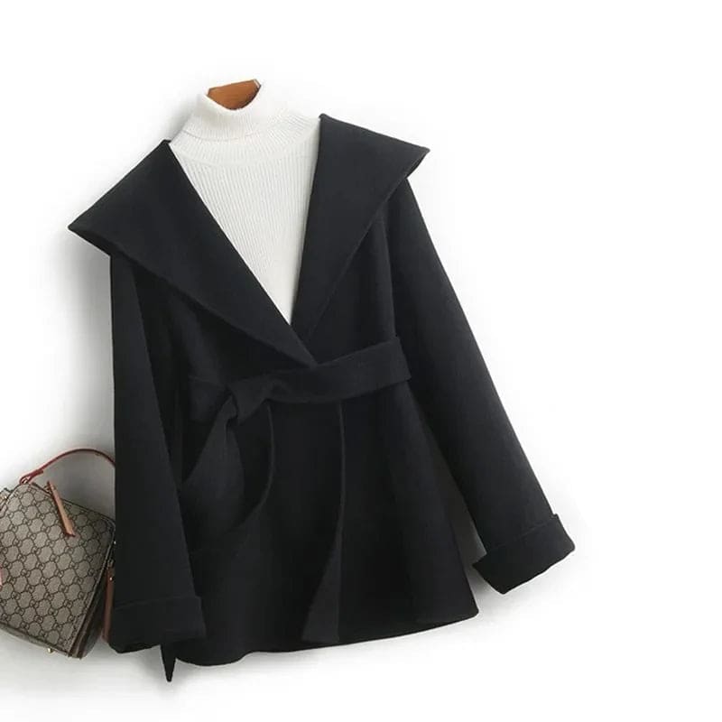 Woman wearing a belted wrap coat with a wide shawl collar, tie belt, and patch pockets over a turtleneck and trousers._19