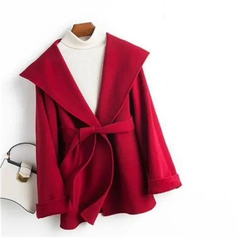 Woman wearing a belted wrap coat with a wide shawl collar, tie belt, and patch pockets over a turtleneck and trousers._21