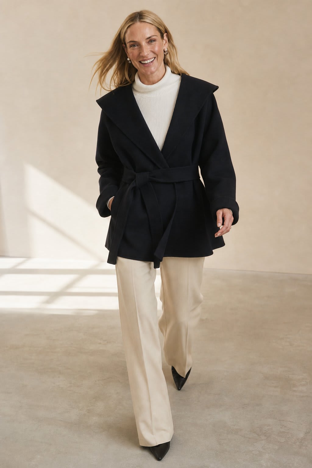 Woman wearing a belted wrap coat with a wide shawl collar, tie belt, and patch pockets over a turtleneck and trousers._6