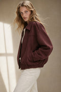 Model wearing a relaxed bomber jacket with lapel collar and zip closure, styled with white pants_0
