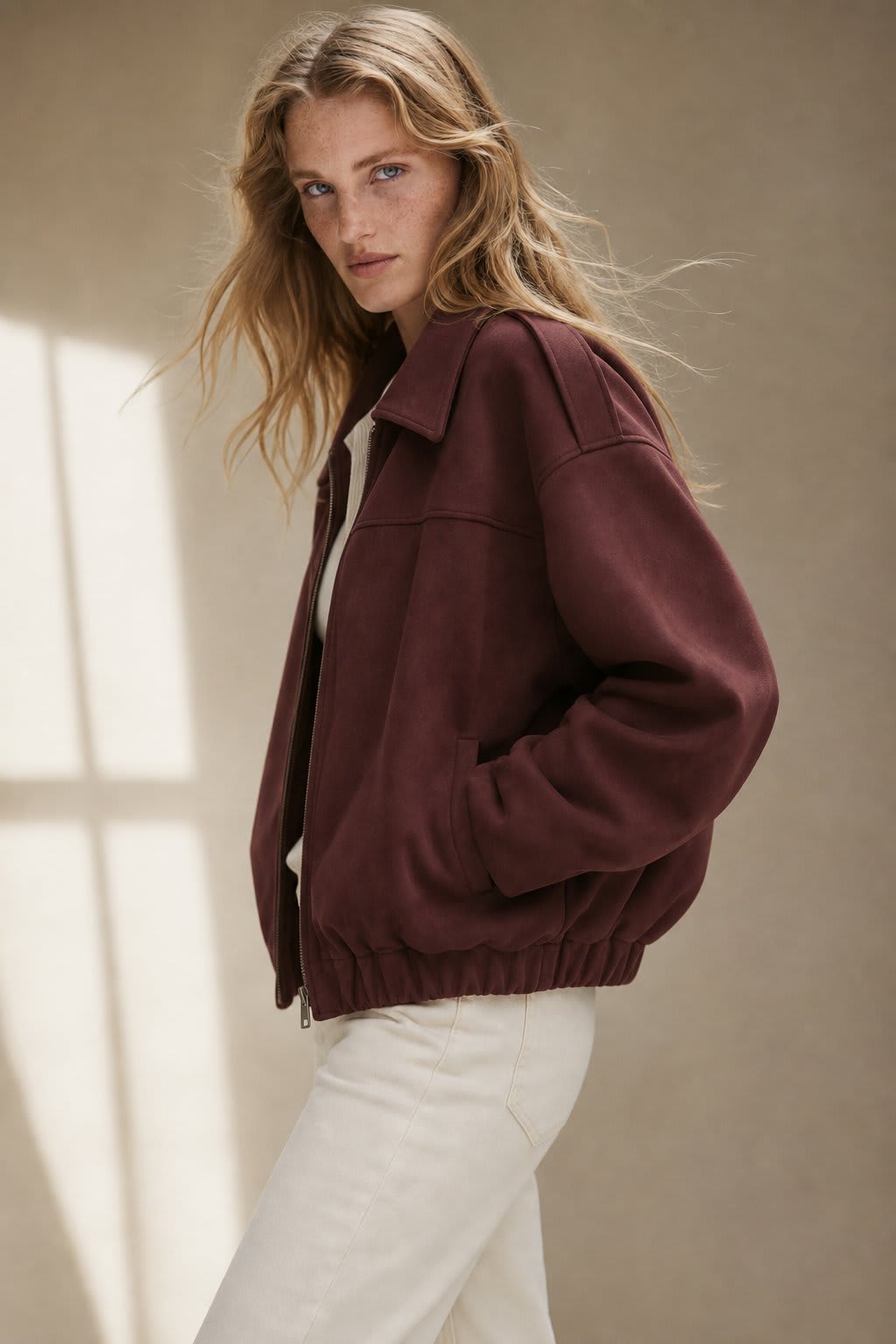 Model wearing a relaxed bomber jacket with lapel collar and zip closure, styled with white pants_0