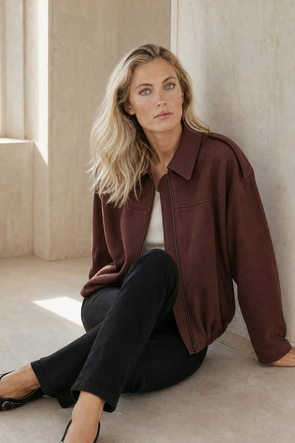 Model wearing a relaxed bomber jacket with lapel collar and zip closure, styled with white pants_1