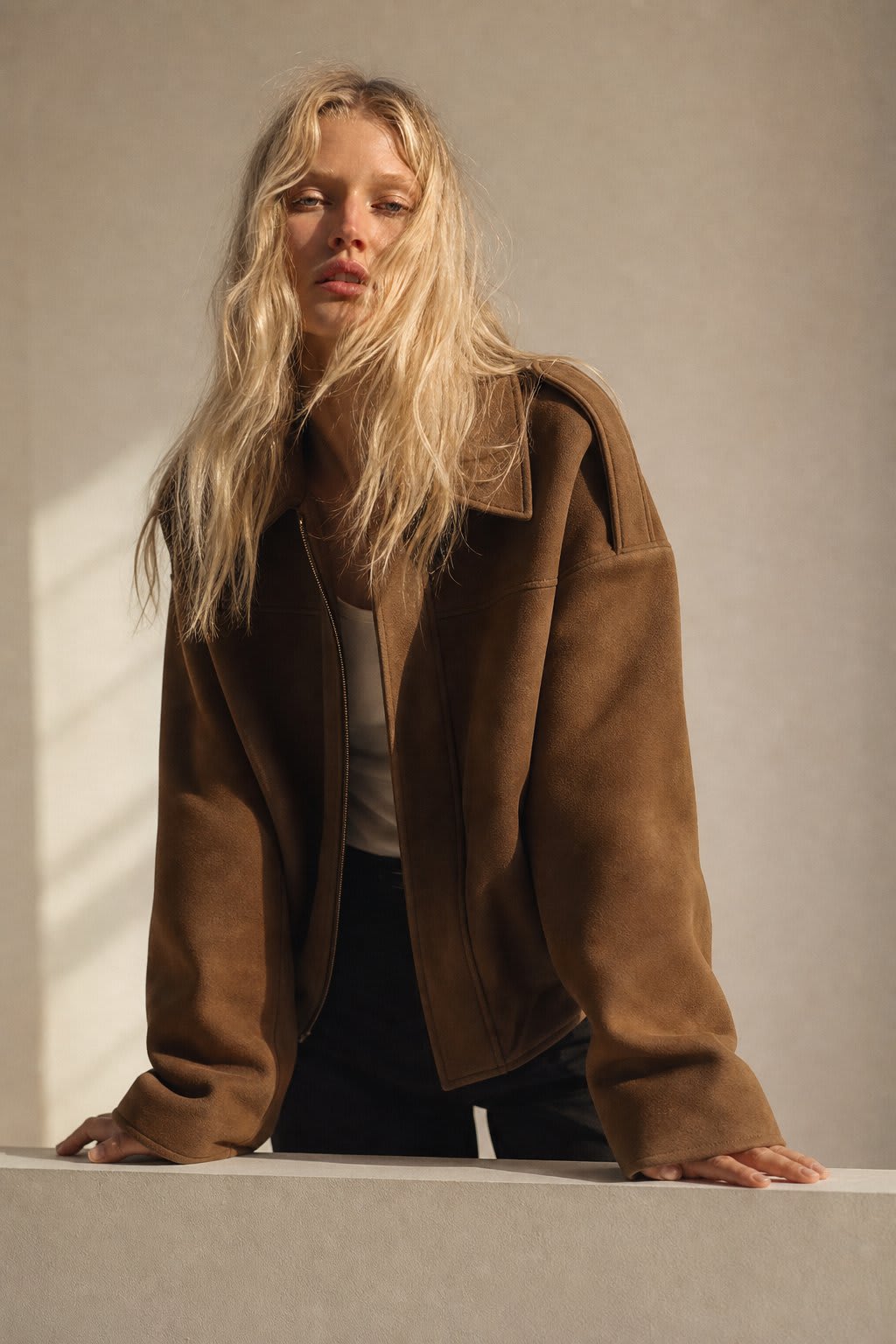 Model wearing a relaxed bomber jacket with lapel collar and zip closure, styled with white pants_2