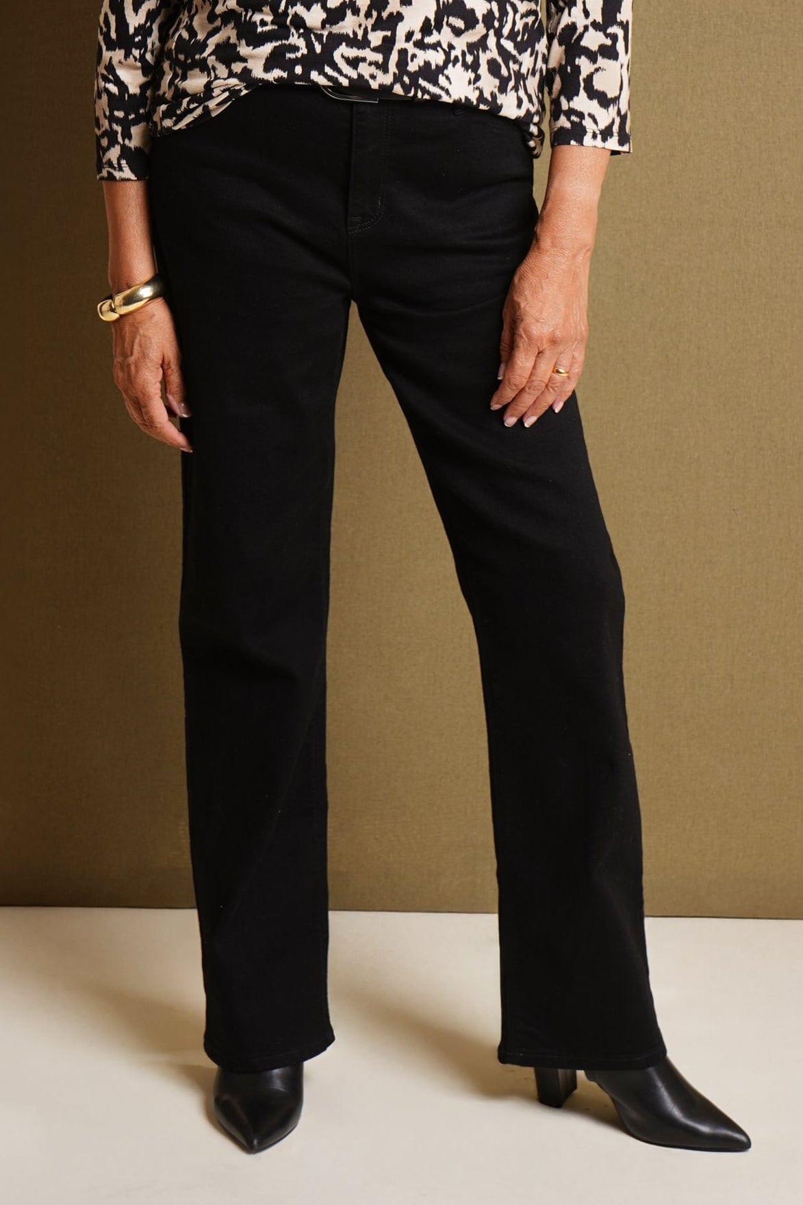Woman wearing black high waisted straight leg jeans with belt loops, a black and cream printed top and black pointed ankle boots._0
