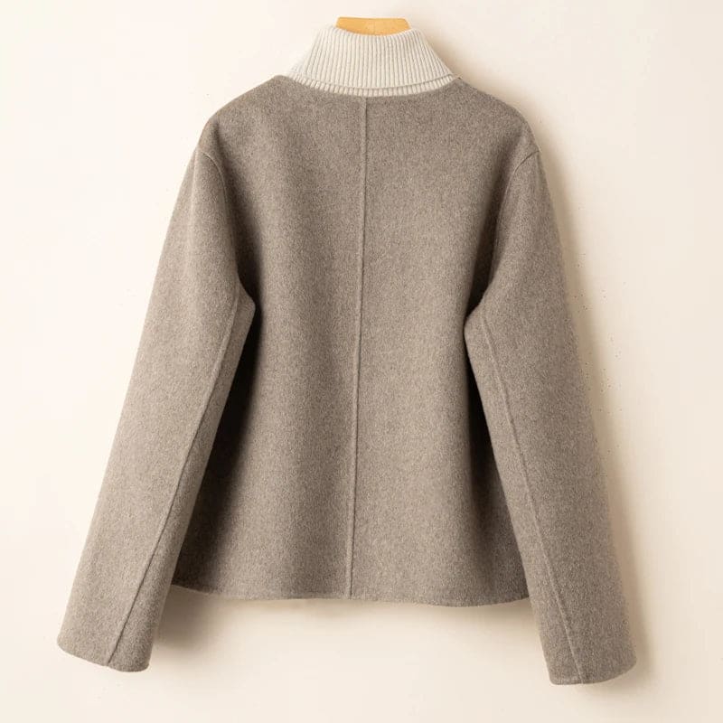 Woman wearing a button-front jacket with round neckline over a turtleneck sweater and beige trousers in natural light_12
