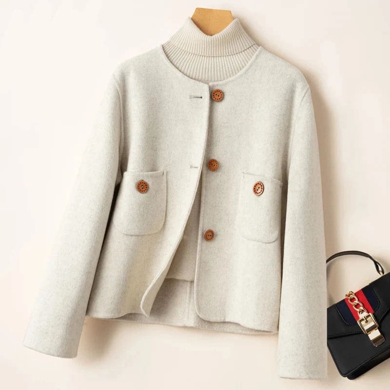 Woman wearing a button-front jacket with round neckline over a turtleneck sweater and beige trousers in natural light_15