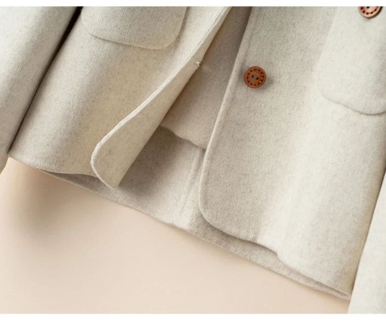 Woman wearing a button-front jacket with round neckline over a turtleneck sweater and beige trousers in natural light_17