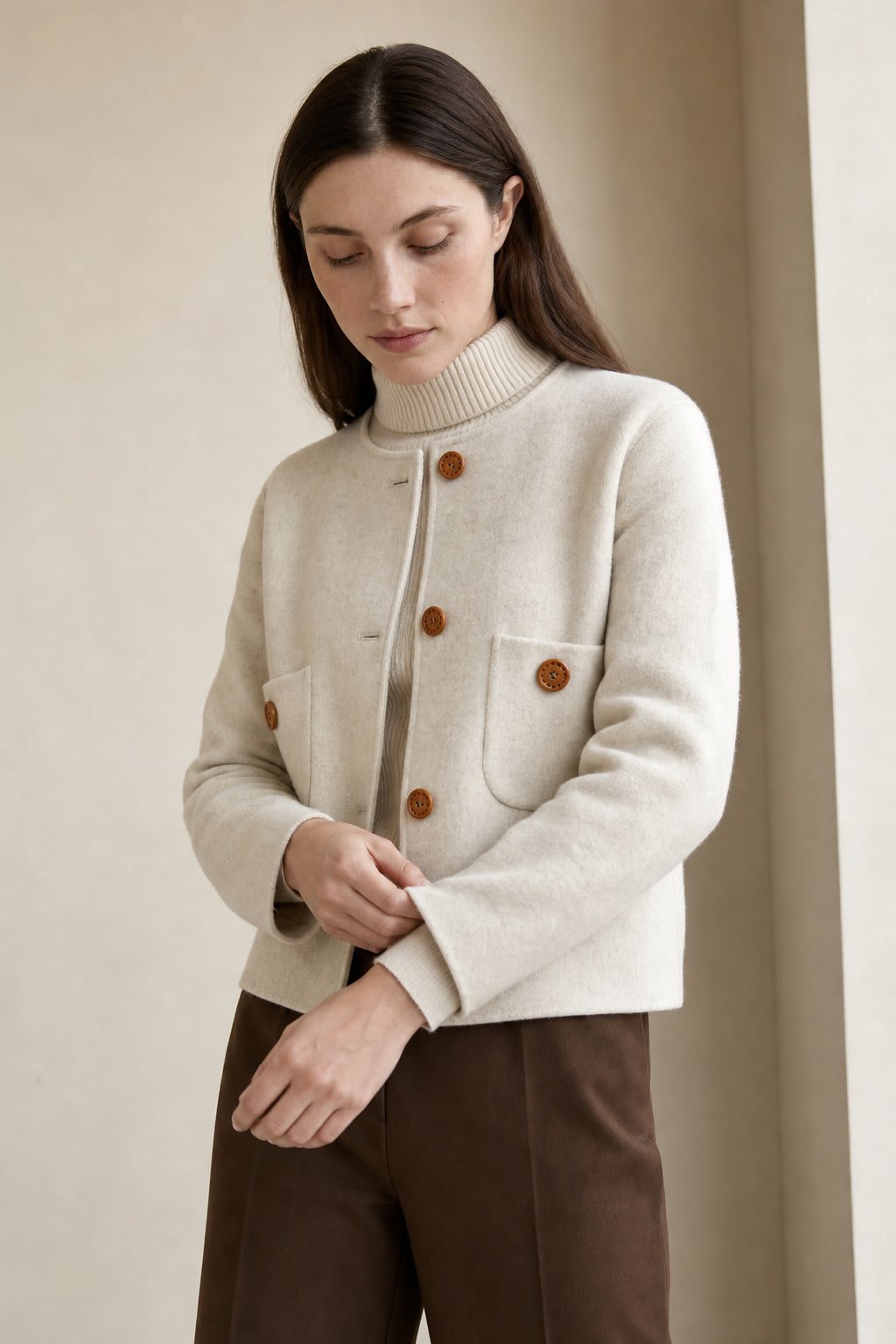 Woman wearing a button-front jacket with round neckline over a turtleneck sweater and beige trousers in natural light_4