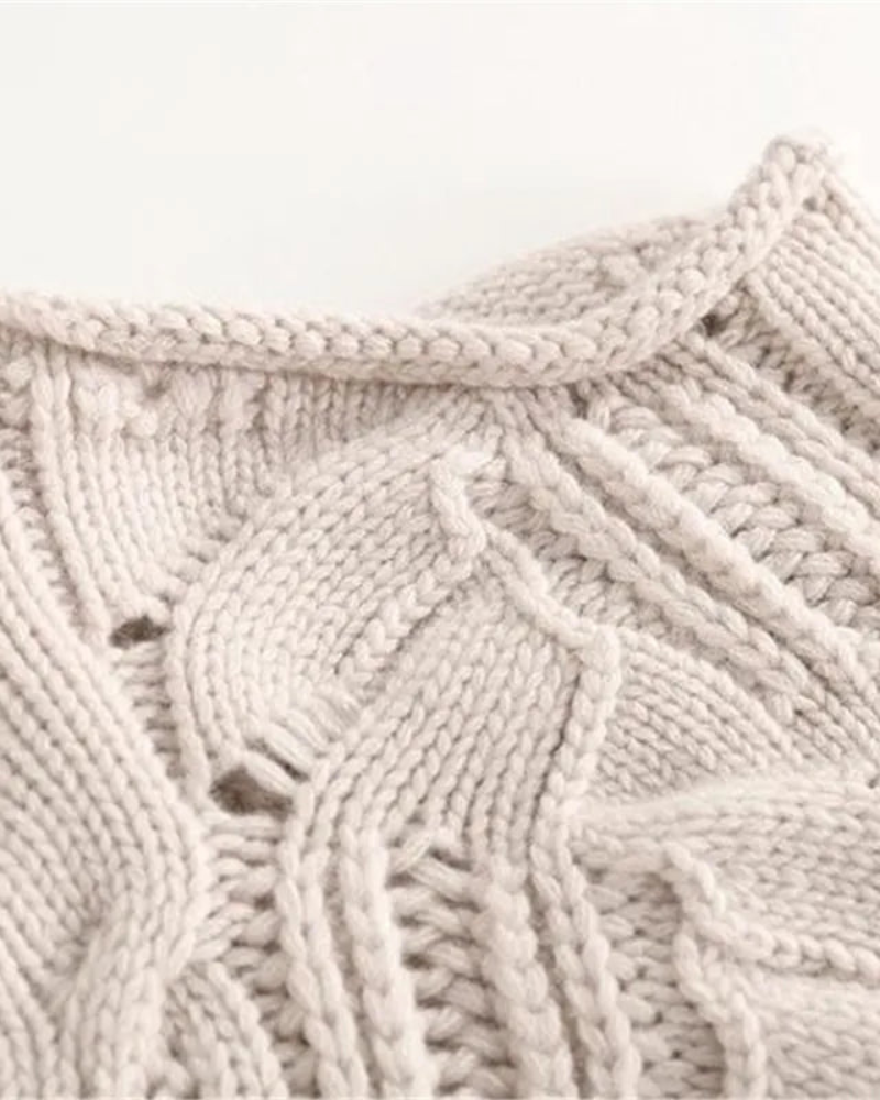 Close-up view of the sweater’s light neutral knit pattern, highlighting interwoven cable stitches and textured loops.