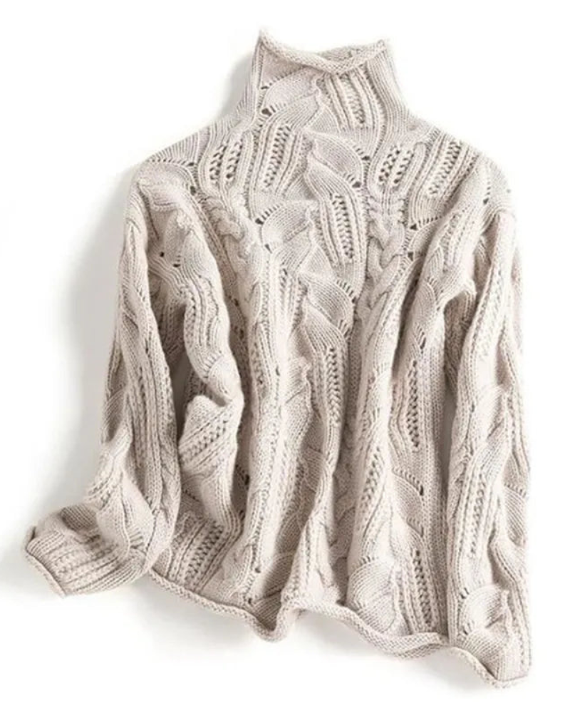 Full view of the light neutral knitted sweater with long sleeves, a high neckline, and prominent braided cable detailing.