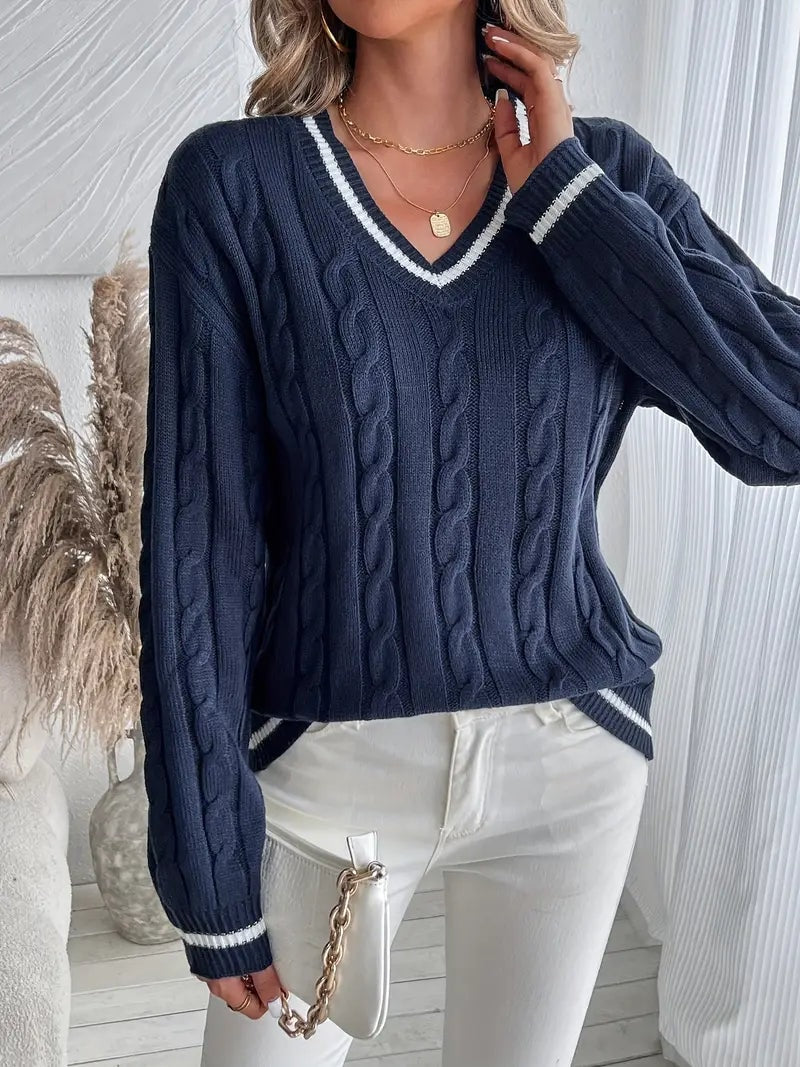 Three-quarter view of a navy cable-knit sweater with contrasting striped neckline and sleeve cuffs.