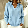 Woman wearing a light blue knit hooded pullover with a deep v-neckline, drawstring hood, front pocket and ribbed cuffs and hem, with white trousers._0