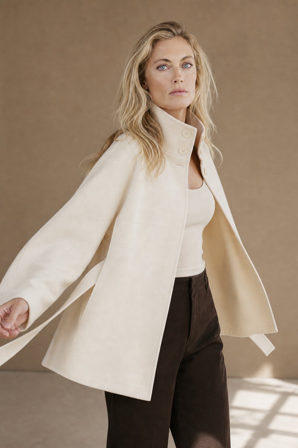 Woman wearing a short cape coat with stand collar, button details, and belted waist._6