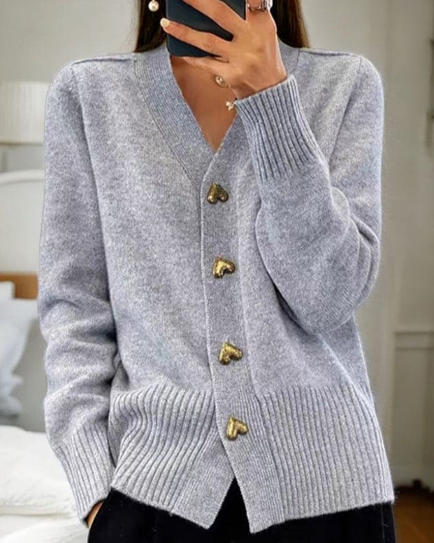 Woman wearing a light grey cardigan with heart-shaped buttons and ribbed detailing at the neckline and cuffs._0