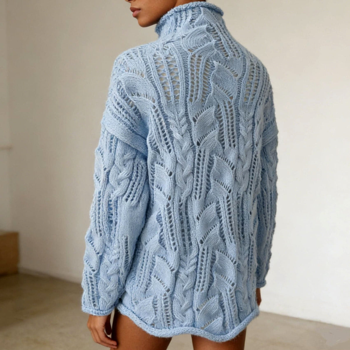 Woman wearing an oversized light blue cable and open knit turtleneck sweater with long sleeves and rolled hem._5