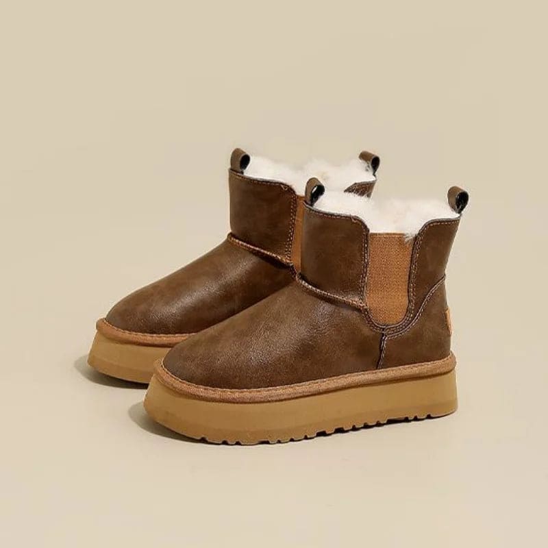 Pair of tan chelsea boots with elastic side panels, chunky platform soles, and soft faux fur lining displayed against a neutral background._0