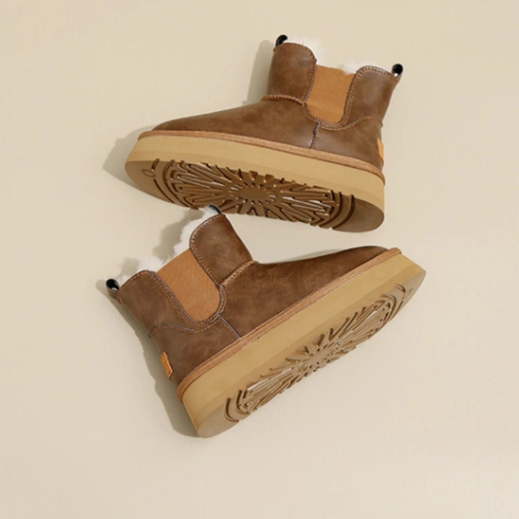 Pair of tan chelsea boots with elastic side panels, chunky platform soles, and soft faux fur lining displayed against a neutral background._1