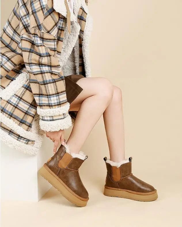 Pair of tan chelsea boots with elastic side panels, chunky platform soles, and soft faux fur lining displayed against a neutral background._10