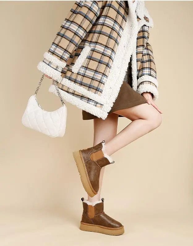 Pair of tan chelsea boots with elastic side panels, chunky platform soles, and soft faux fur lining displayed against a neutral background._11