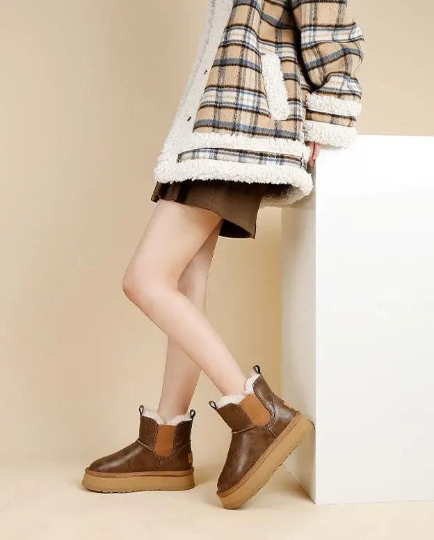 Pair of tan chelsea boots with elastic side panels, chunky platform soles, and soft faux fur lining displayed against a neutral background._12